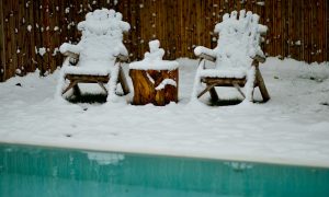 photo de 2 chaises en bois au bord d'une piscine pour l'article de blog guide hivernage de Aquatech